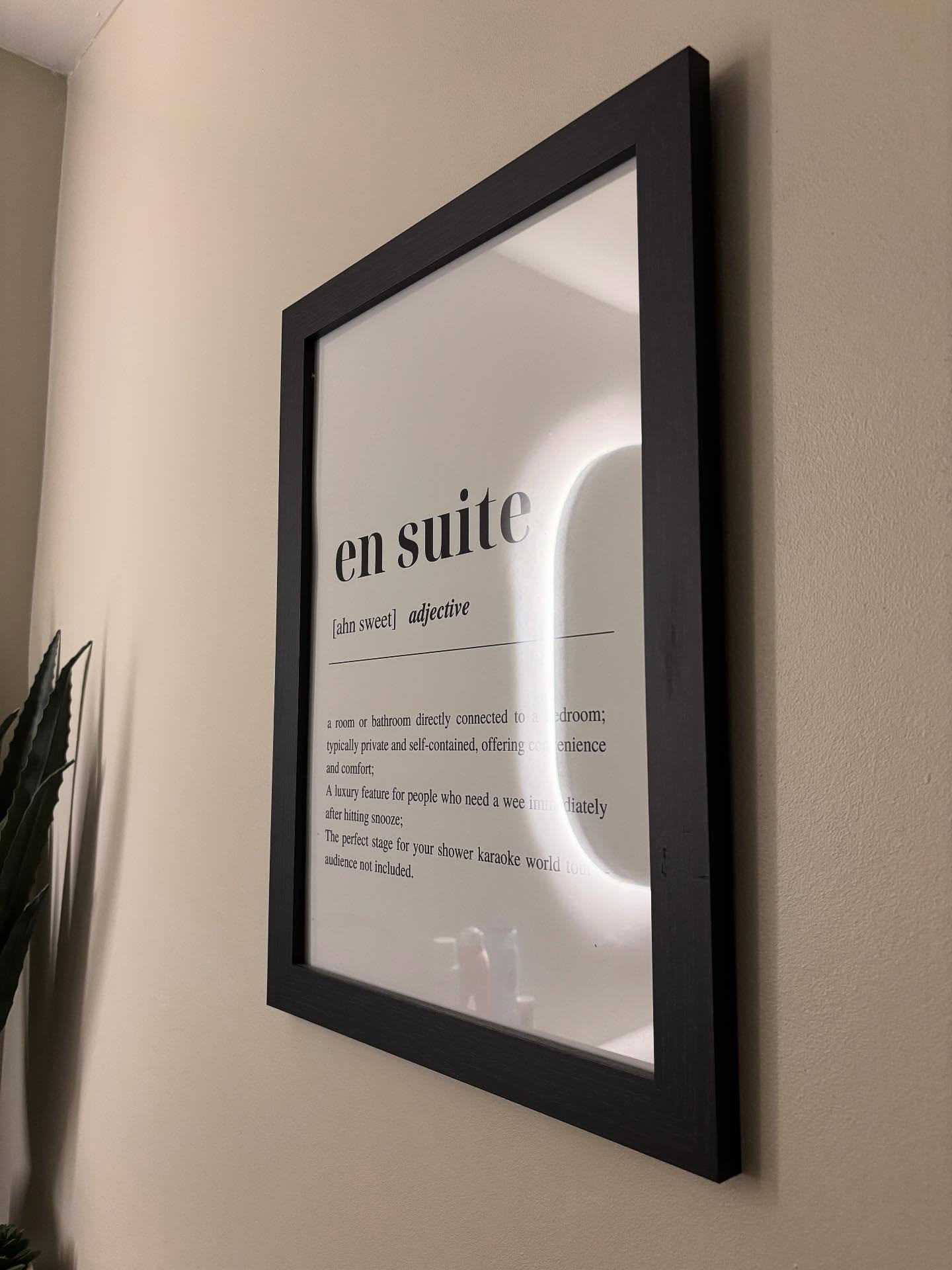 Black framed 'en suite' definition print hanging on a bathroom wall